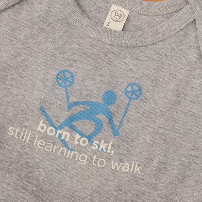 Grey baby onesie with a blue skier graphic and ‘born to ski. still learning to walk’ lettering.