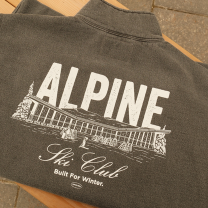 Black Sand Alpine Ski Club quarter-zip sweater with a white chalet back graphic and ‘Built For Winter’ lettering.
