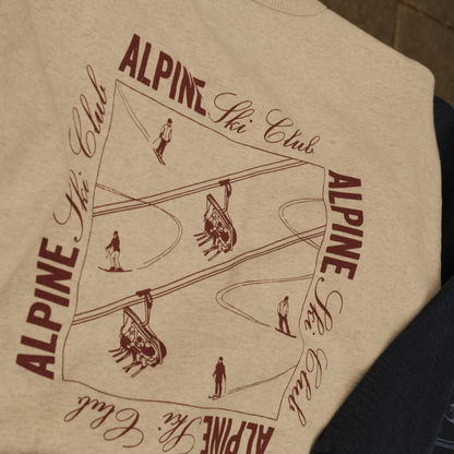 Cream Alpine Ski Club crewneck sweatshirt with a burgundy back graphic of skiers and chairlifts.